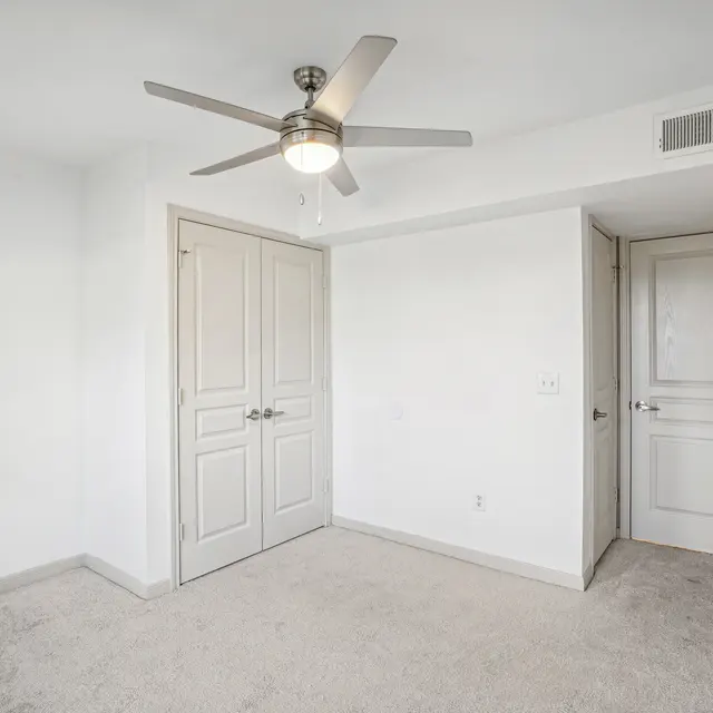 A room with a ceiling fan and two doors.